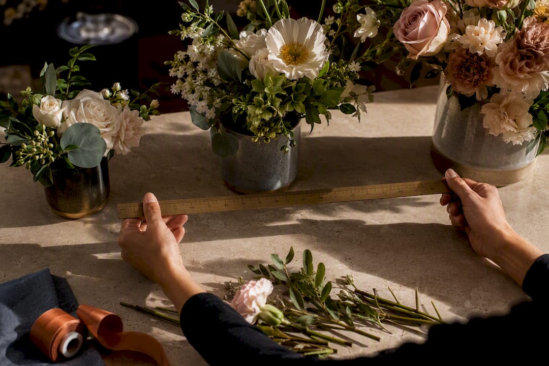 Florist measuring cropped flower arrangements