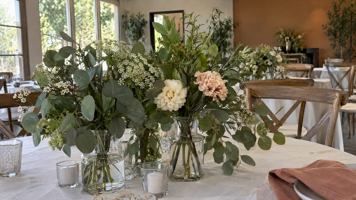 Greenery-forward wedding centerpiece in reusable glass